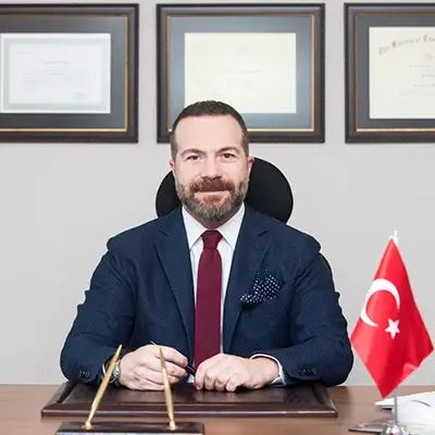 Prof. Dr. Ali Civelek çalışma masasında, yanında Türk bayrağı