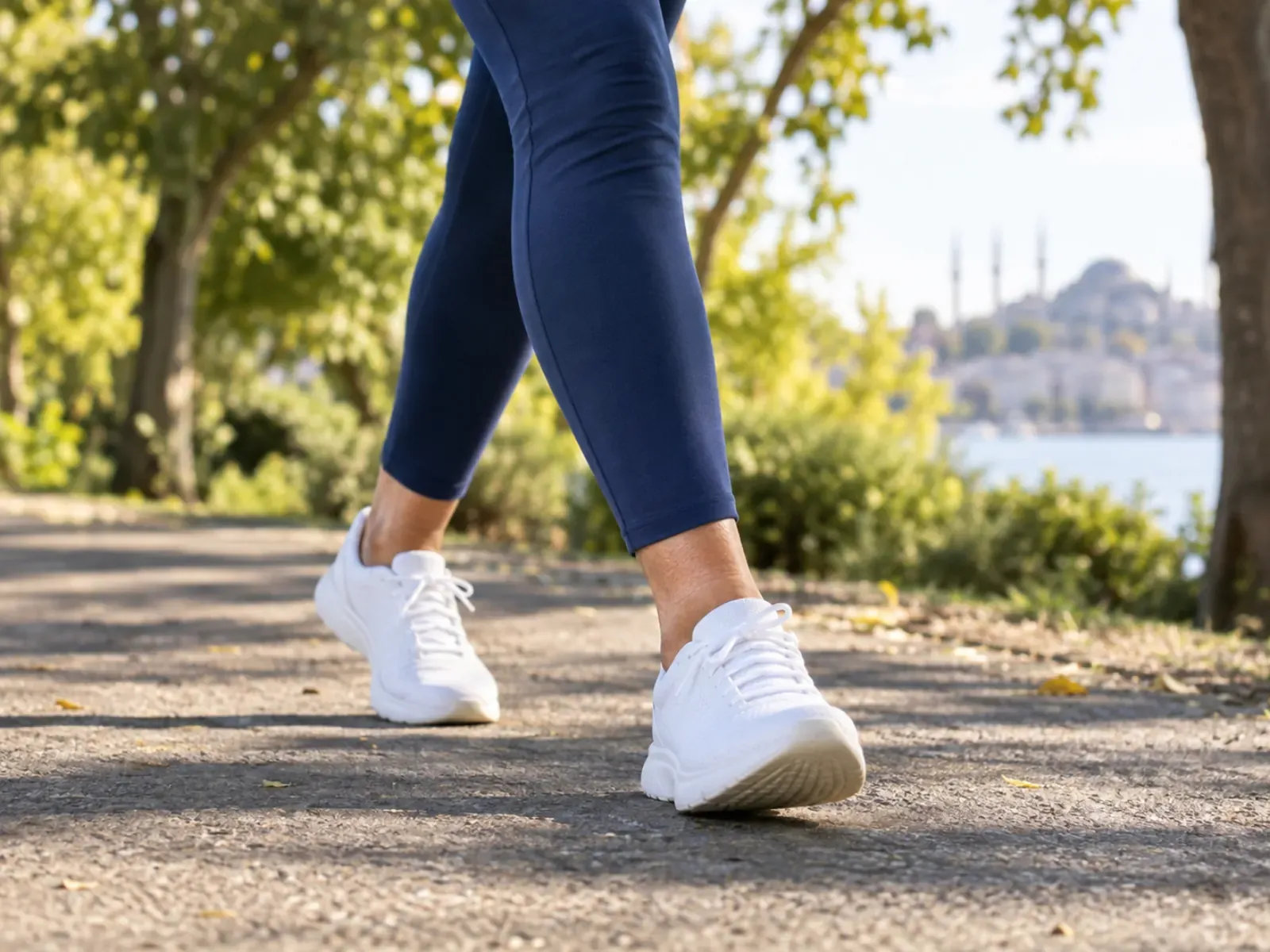 Parkta tempolu yürüyen bir kadının bacakları, lacivert tayt ve beyaz spor ayakkabı